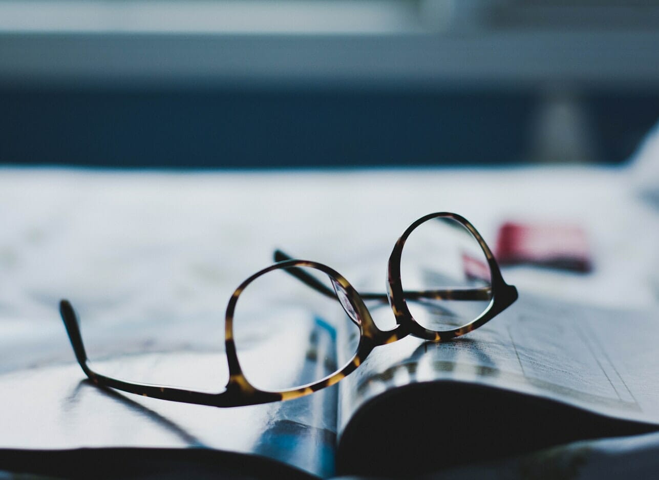 A pair of glasses laid on top of a book by an insider.