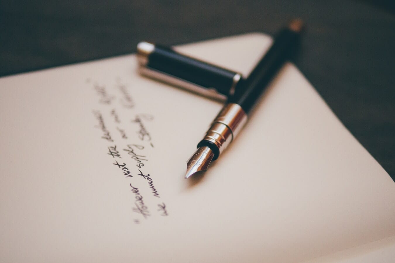 A fountain pen sits on top of an open notebook.