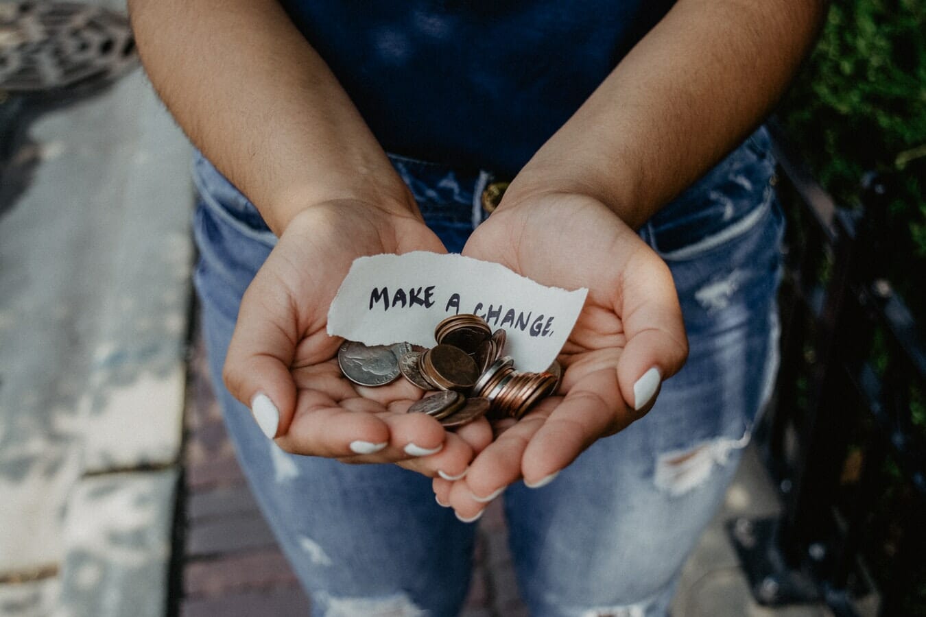A woman's hands holding coins and a note that says make a difference.