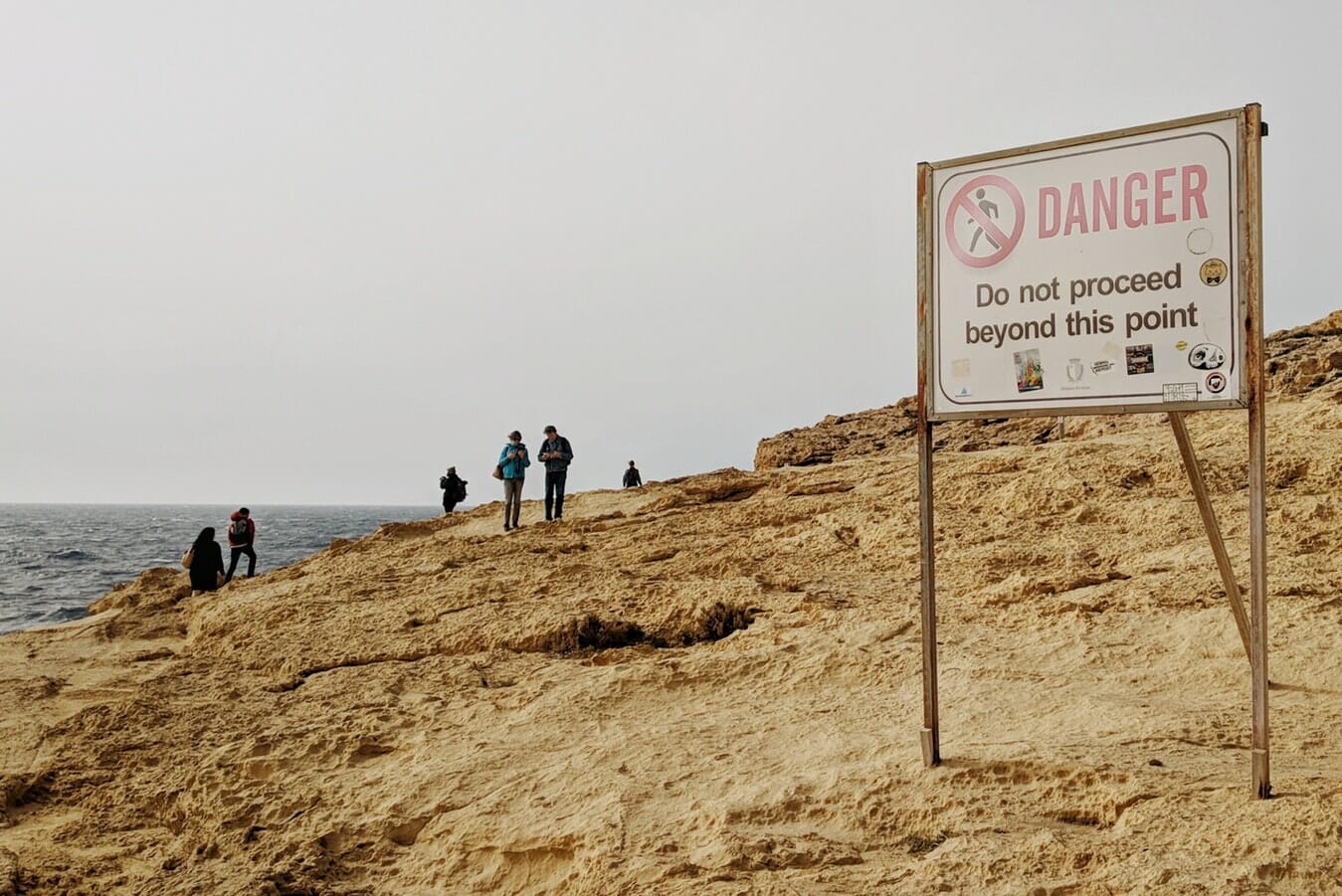 A sign on a cliff warning people of danger.