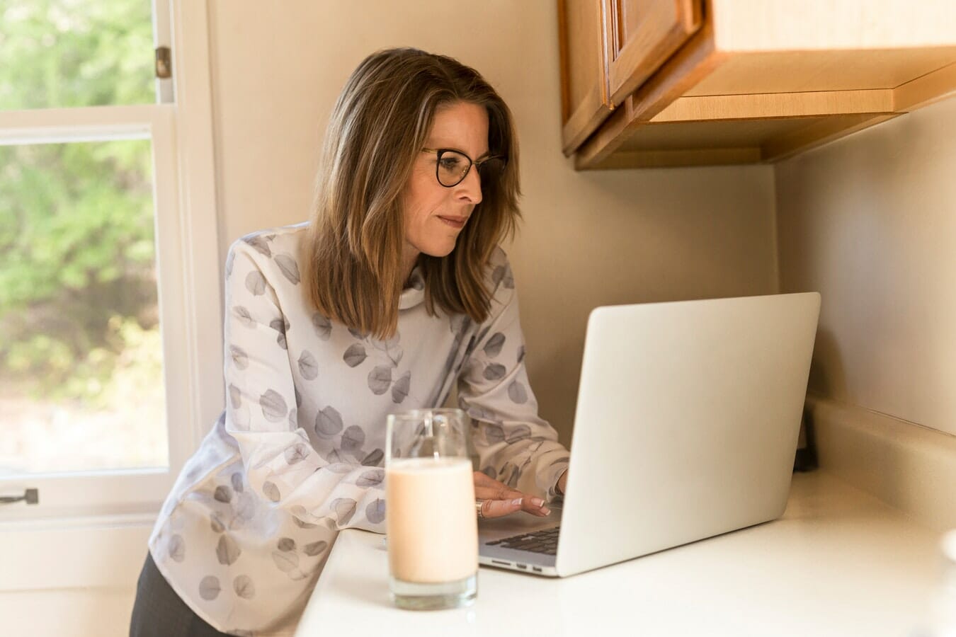 A woman using a laptop in her kitchen.
