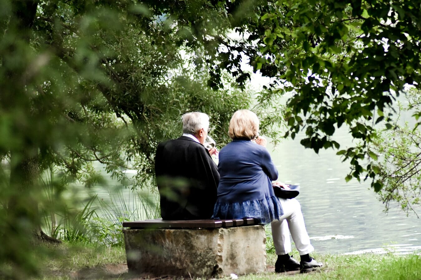 A couple sitting on a bench next to a lake.