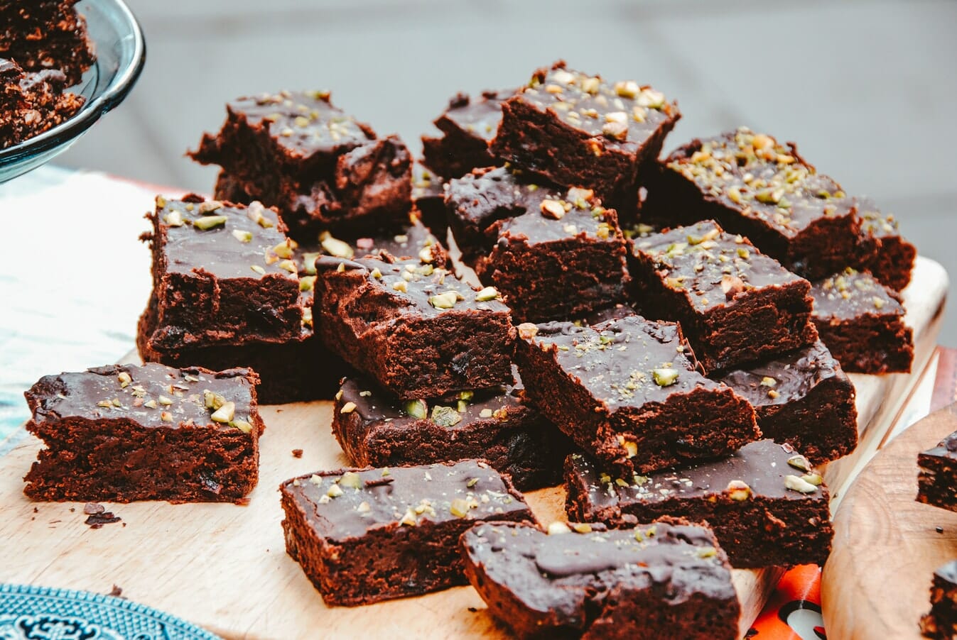 Chocolate brownies with pistachios on a wooden cutting board.
