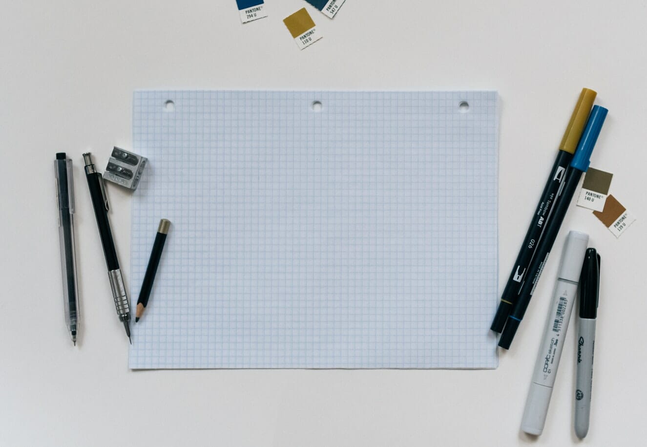 A piece of paper with pens and pencils on a white surface.