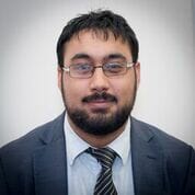 A man in a suit and tie standing in front of a wall.