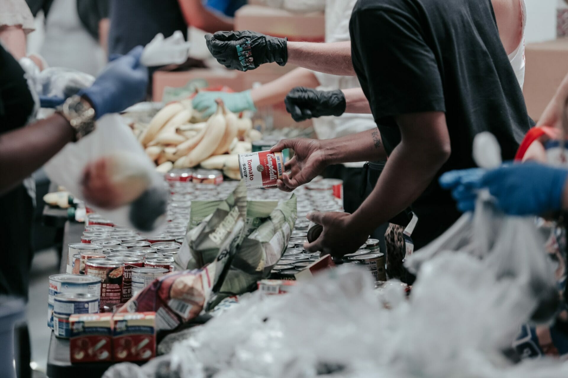 A group of people in black gloves sorting food for charities.