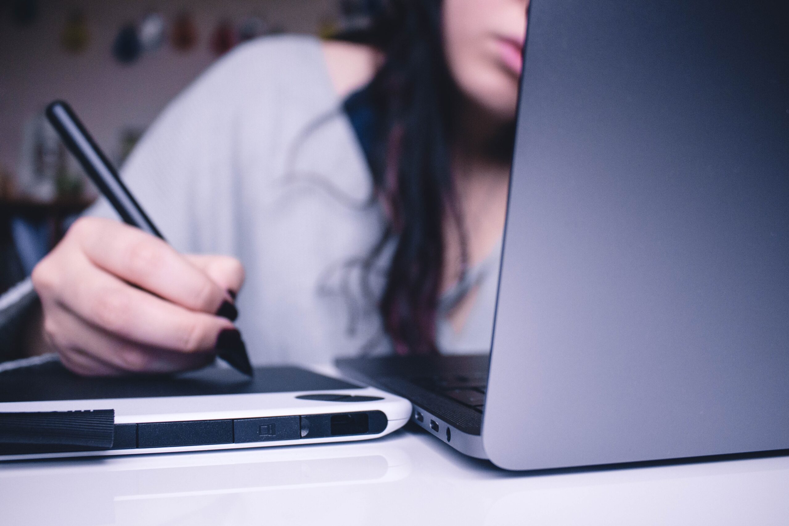 A person using a stylus on a laptop for art.