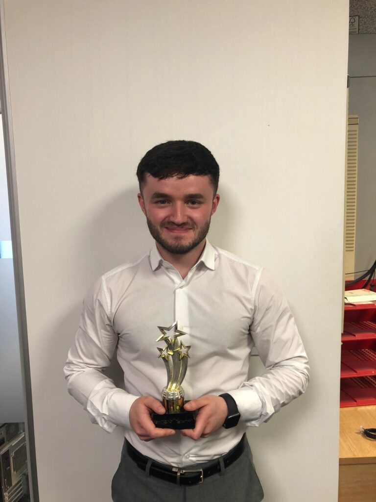 A man holding a trophy in an office.
