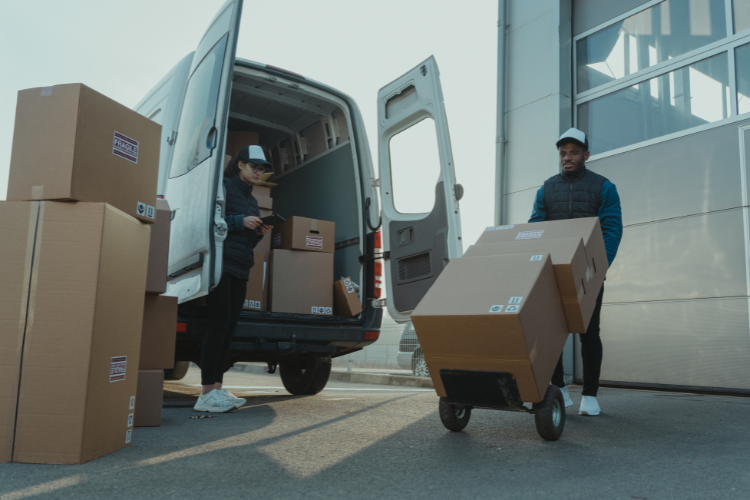 Two workers loading boxes into a van.